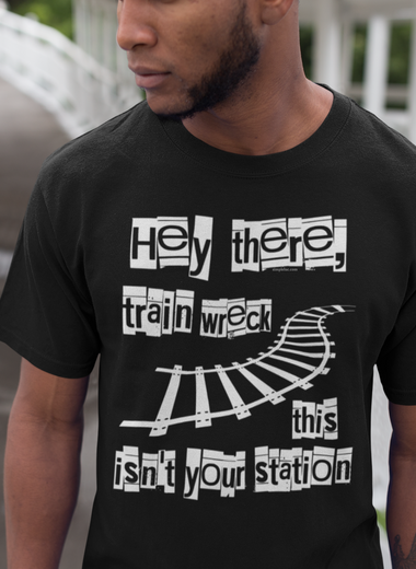 A confident man standing on a staircase wearing a white 'Hey There, Train Wreck, This Isn't Your Station' tee