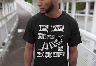 A confident man standing on a staircase wearing a white 'Hey There, Train Wreck, This Isn't Your Station' tee